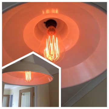 A filament bulb glowing inside a coral pendant shade