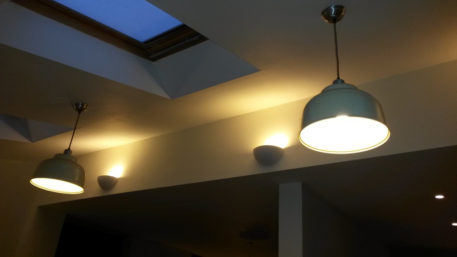 Lawrence's own photo: two lit pendant lights and wall lights under a skylight